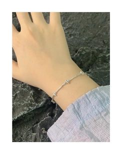 Close-up of S925 sterling silver beaded bar bracelet worn against rock background