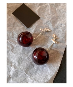 Detailed close-up of glossy red resin cherry earrings with elegant silver metal leaves