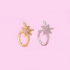 Detail of star-shaped clip-on earrings with pave cubic zirconia in gold and silver finish