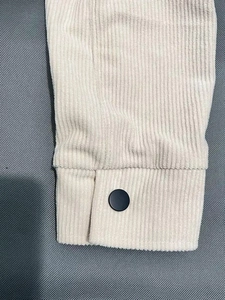 Detailaufnahme der Cordstruktur und des schwarzen Knopfes am beigen Hemdärmel der Jacke