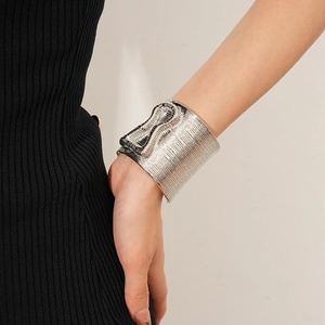 Close-up of a wide silver cuff bracelet with textured linear patterns on a model's wrist