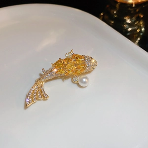 Detailed view of a golden koi fish brooch with yellow zircons and a white pearl accent