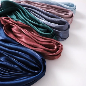 Detailed view of various colorful silk-like scarves showing smooth texture and high shine