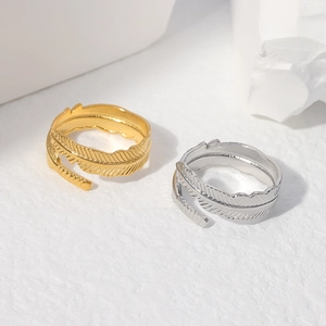 Detailed close-up of adjustable feather-shaped rings in gold and silver stainless steel