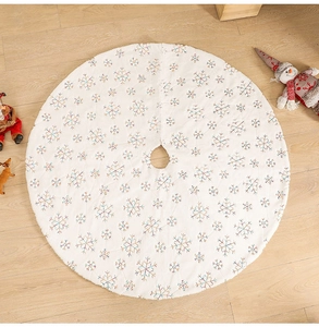 Detail of white plush Christmas tree skirt with colorful snowflake sequins on wood floor