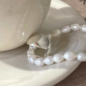 Minimalist S925 sterling silver ball earrings and pearl necklace on a ceramic plate