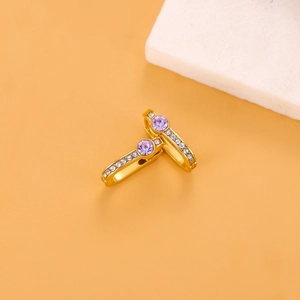 Macro shot of gold hoop earrings featuring a purple round stone and pavé zircon accents