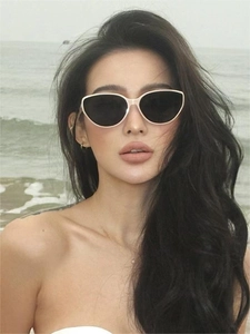 Close-up of stylish cat-eye sunglasses with cream frames worn in beach natural sunlight