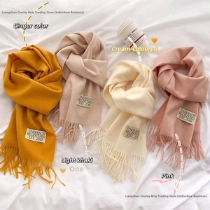 Flat lay of soft cashmere-feel scarves with fringe and labels in warm autumn colors