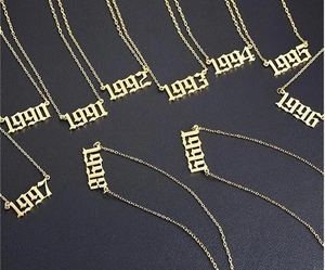 Vue détaillée de colliers en acier doré avec pendentifs d'année de naissance de 1990 à 1999
