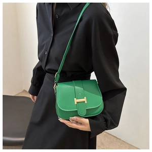 Detail of bright green crossbody bag with a geometric gold buckle on a black outfit