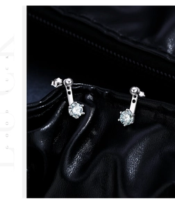 Macro shot of 925 silver stud earrings with blue-green moissanite on black leather