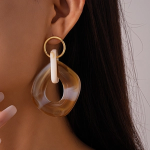 Detail showing amber transparent resin pendant and gold metal parts of these earrings