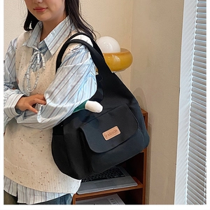Lifestyle shot of a black canvas tote bag with FASHION leather tag and doll charm