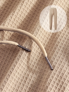 Detail of waffle knit fabric texture and drawstring tips on khaki leisure jogger pants