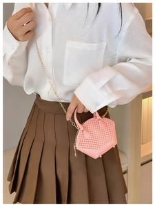 Mini pink jelly shell bag with gold chain strap shown on model in cozy indoor setting