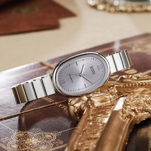Close-up of vintage oval silver watch with lavender dial on a gold frame and books
