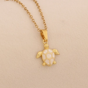 Detail shot of golden sea turtle pendant featuring white shell inlay on a gold chain