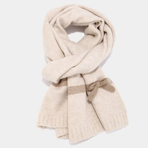 Detailed view of beige knitted scarf featuring thick texture and 3D bow decoration