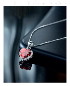 Macro view of a classic heart-shaped red zircon pendant with silver box chain and reflection