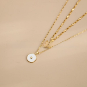 Detail of 18K gold-plated layered necklace with heart and white enamel pendants
