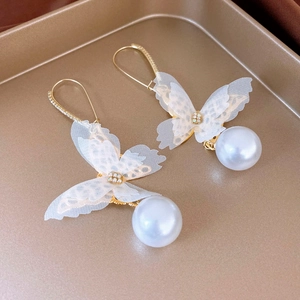 Detailed view of delicate white lace butterfly earrings with hanging pearls and gold hooks