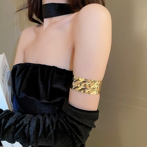 Detailed view of golden irregular crinkle texture on a metal upper arm bracelet