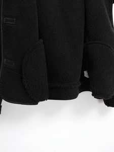 Detail view of black faux suede jacket hem showing fleece texture and stitching