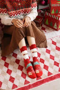 Detail of red Christmas socks with Santa and reindeer motifs and white plush cuffs