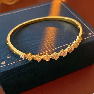 Detailed macro view of gold-plated heart-shaped bangle with micro-pave zircon settings