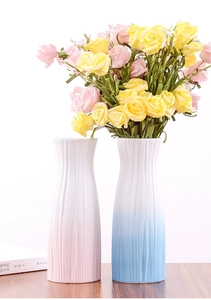 Detail of pink and blue-white textured ceramic vases with roses on wooden desk