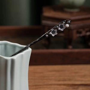 Detail of elegant Chinese style hair pin with black body, floral petals and pearls
