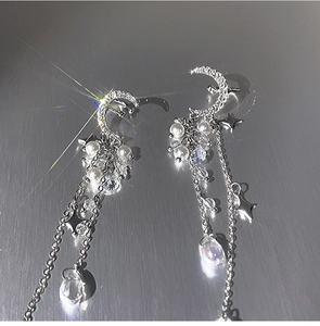 Detail of silver moon and star earrings with zircon tassels and pearl accents