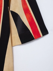 Detailed close-up of striped sleeve cuffs in red, black and beige textured fabric