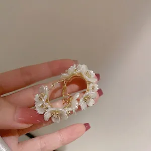 Gold plated floral earrings featuring white petals and sparkling crystal accents