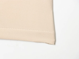 Gros plan détaillé du tissu en sergé beige et des coutures soignées du pantalon long