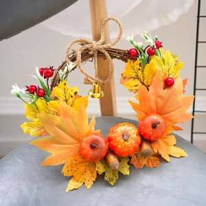 Autumn wreath with pumpkins, maple leaves, and berries hanging on a wooden chair back