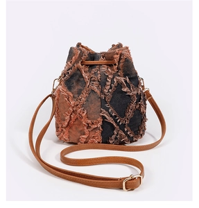 Detail of vintage tie-dye denim bucket bag featuring frayed fringe and leather strap