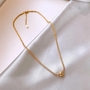 Detail shot of a gold beaded titanium necklace draped on smooth white satin fabric