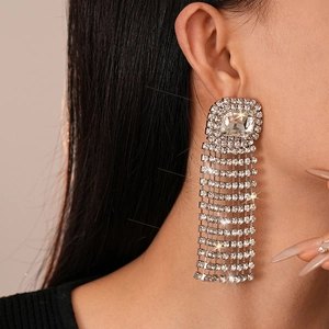 Close-up of sparkling square rhinestone tassel earrings worn on a model's ear