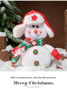 Detail of plush snowman Christmas gift bag with knitted scarf and fur hat on snow