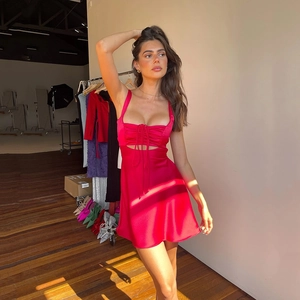 Detail of red satin dress with drawstring bust and cutout design in bright sunlight