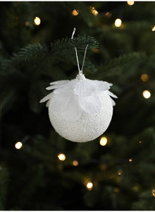 Detail of white foam Christmas ball with glitter petals hanging on tree branch