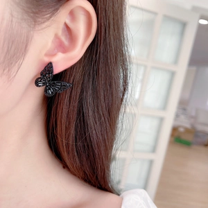 Close-up of elegant black butterfly stud earrings with zircon inlay worn by model