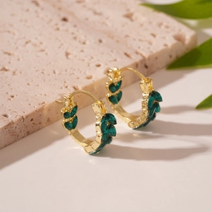 Detail of vintage gold huggie earrings with wheat-shaped green crystals on stone base