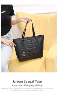 Detail of black quilted leather tote bag with embroidery and circular metal pendant