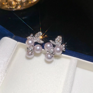 Detailed close-up of butterfly pearl earrings with silver base and sparkling crystals