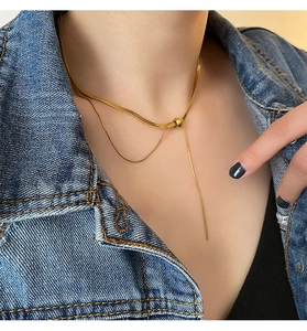 Detail of a gold snake chain lariat necklace featuring a sleek adjustable slider bead