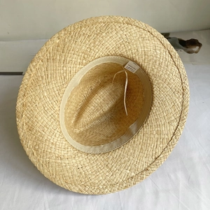 Detailed view of 100% natural raffia straw hat weaving and internal quality label