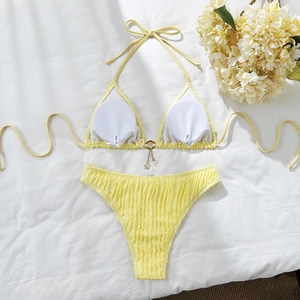 Detailed view of yellow ribbed bikini with gold star pendant and metallic ring connector